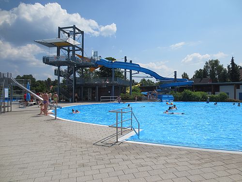 Blick auf das Nichtschwimmerbecken im Egrensisbad mit Wasserrutsche im Hintergrund.