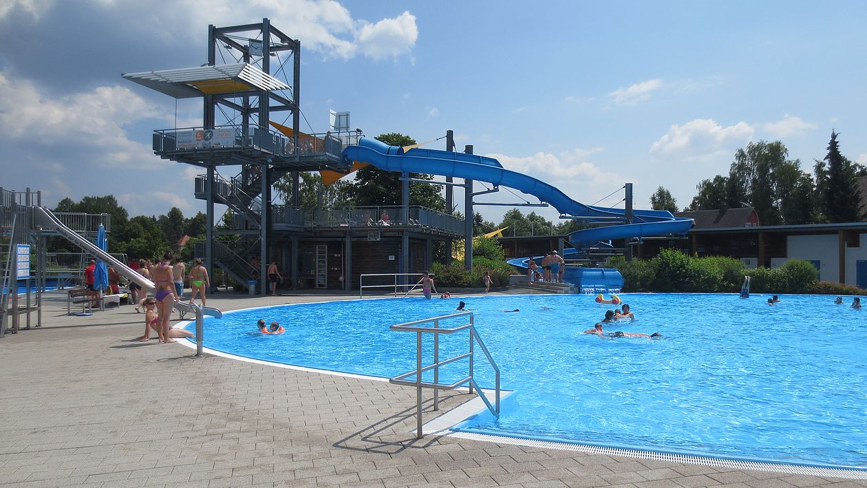 Blick auf das Nichtschwimmerbecken im Egrensisbad mit Wasserrutsche im Hintergrund.